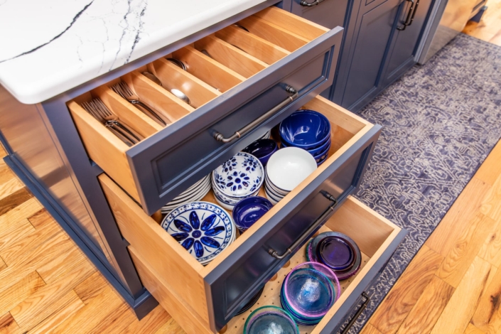 blue kitchen island with dishware in drawers