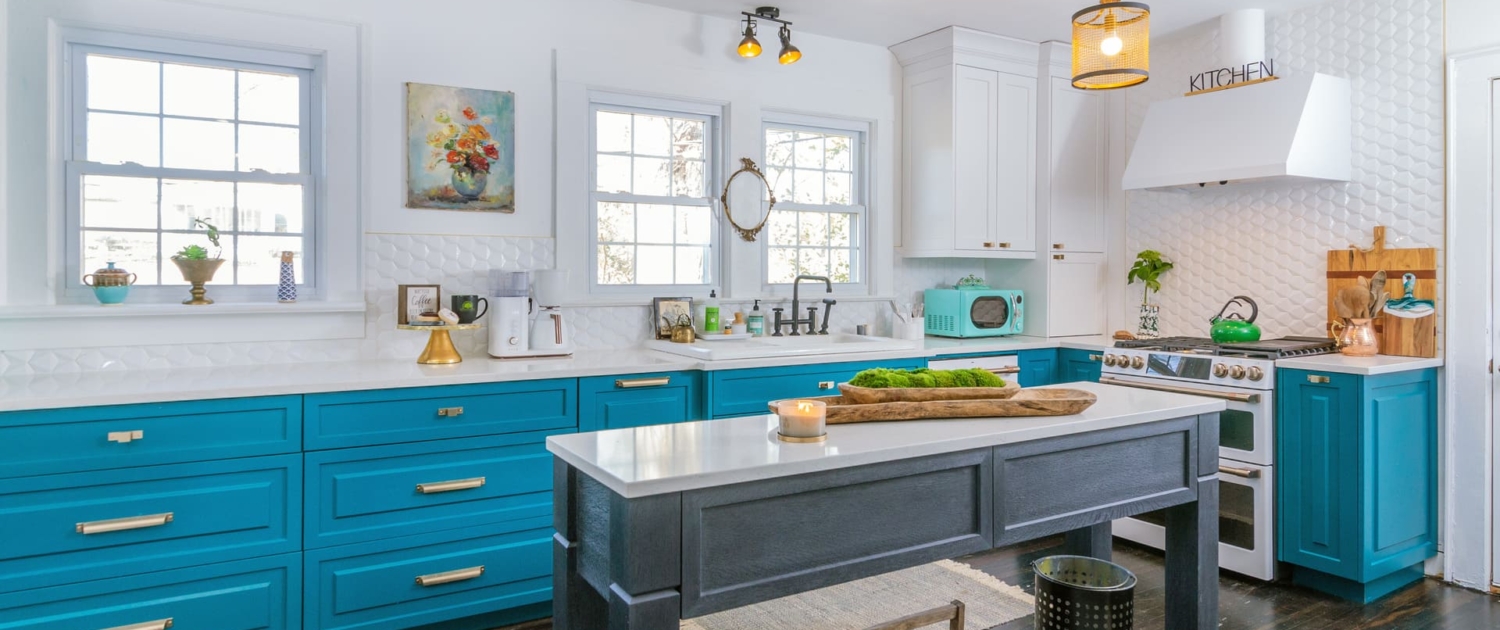 teal kitchen with gold lights and an island