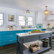 teal kitchen with gold lights and an island