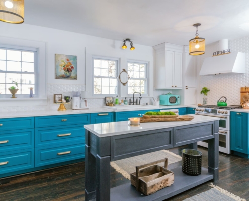 teal kitchen with gold lights and an island