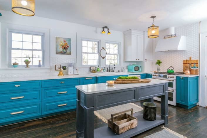 teal kitchen with gold lights and an island