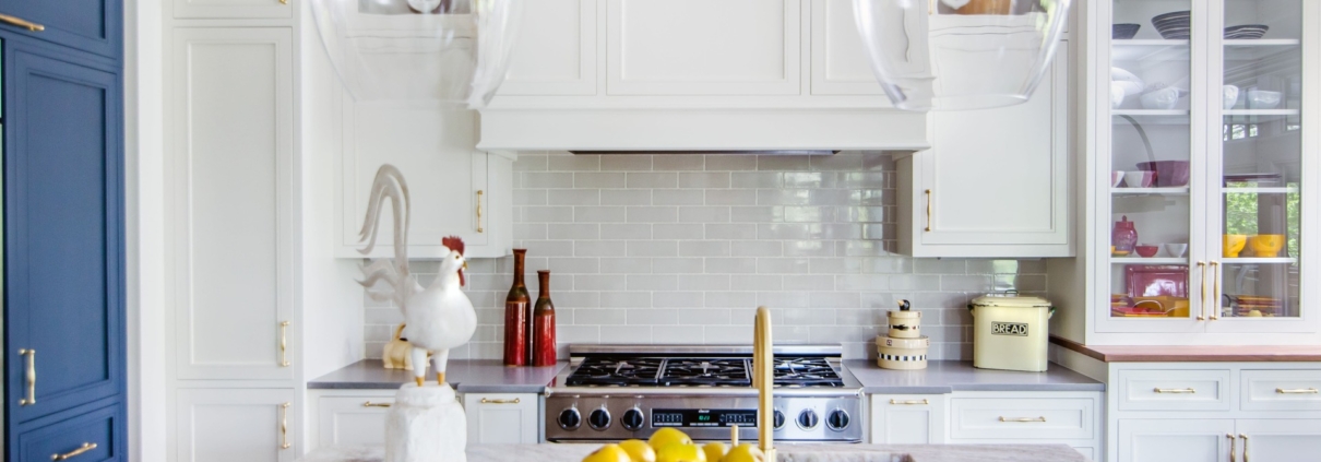 A kitchen with white and blue cabinetry and with glass front doors