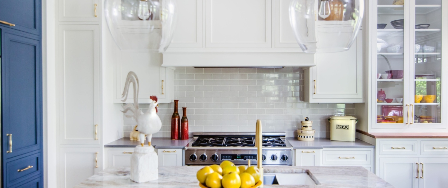 A kitchen with white and blue cabinetry and with glass front doors