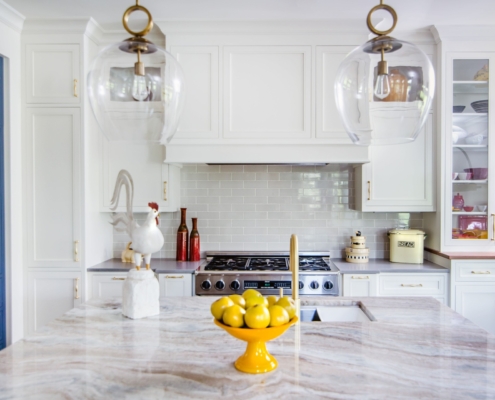 A kitchen with white and blue cabinetry and with glass front doors