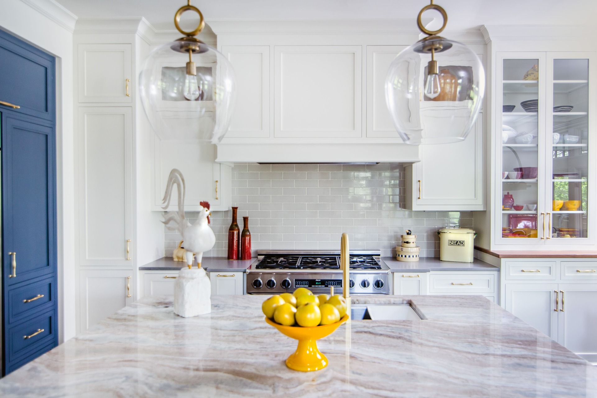 A kitchen with white and blue cabinetry and with glass front doors