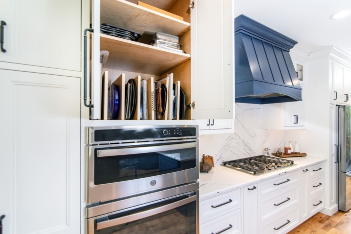 white kitchen with a blue hood and pan storage
