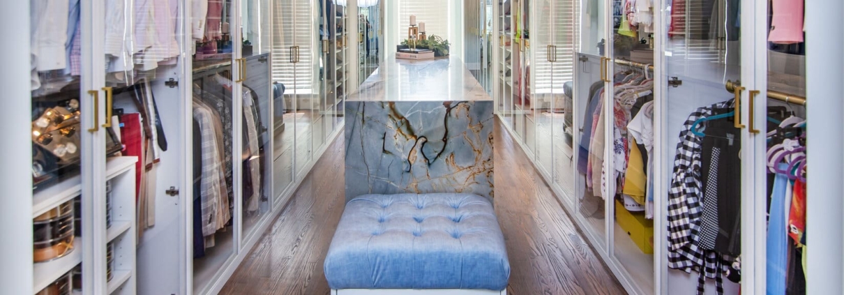 Custom closet with glass doors and an island