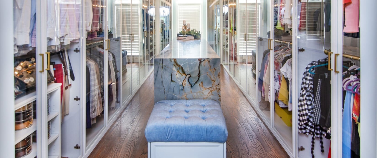 Custom closet with glass doors and an island