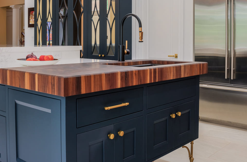 Blue kitchen island with gold hardware and a butcher block countertop