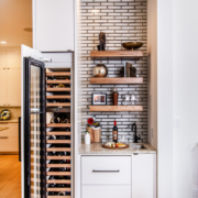 A wet bar with floating shelves and a wine cooler with a paneled door