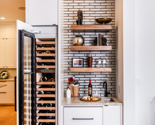A wet bar with floating shelves and a wine cooler with a paneled door
