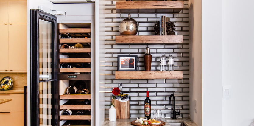 A wet bar with floating shelves and a wine cooler with a paneled door