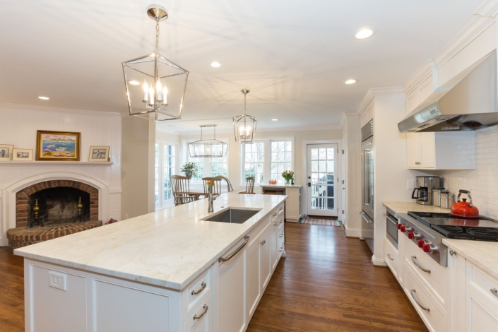 white kitchen, a brick fireplace, and a dining room