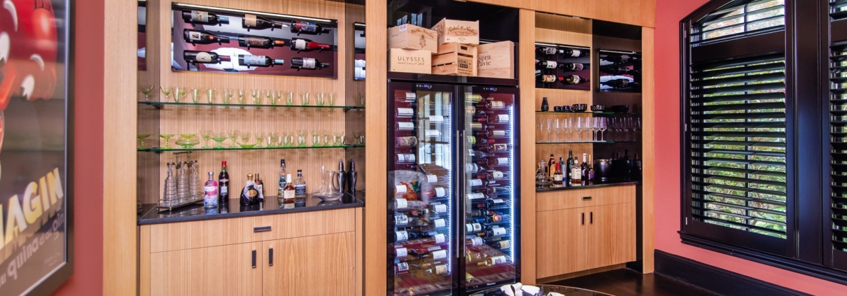 A custom wine room with oak cabinetry and with a built in wine cooler