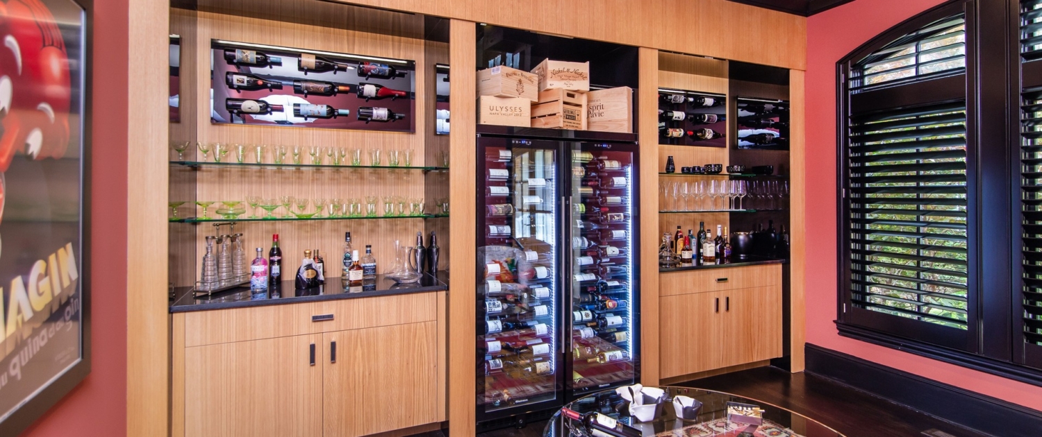 A custom wine room with oak cabinetry and with a built in wine cooler