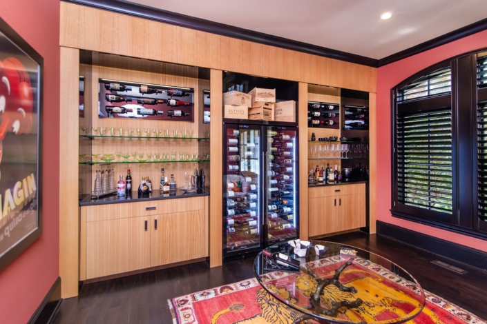 A custom wine room with oak cabinetry and with a built in wine cooler