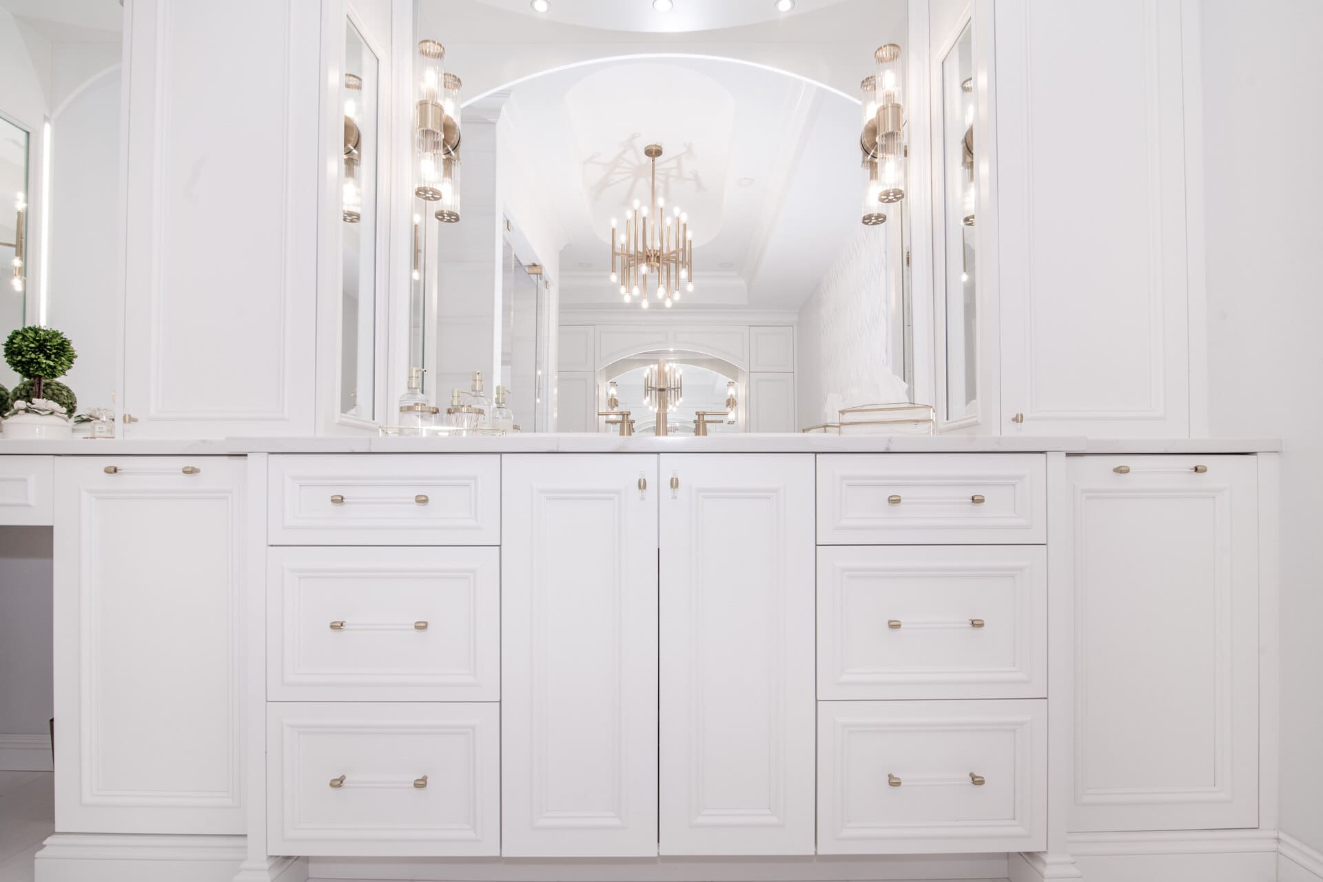 White bathroom vanity with gold hardware and a large mirror