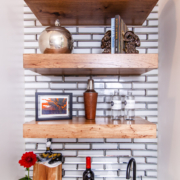 A wet bar with wood floating shelves and decor pieces displayed all on them