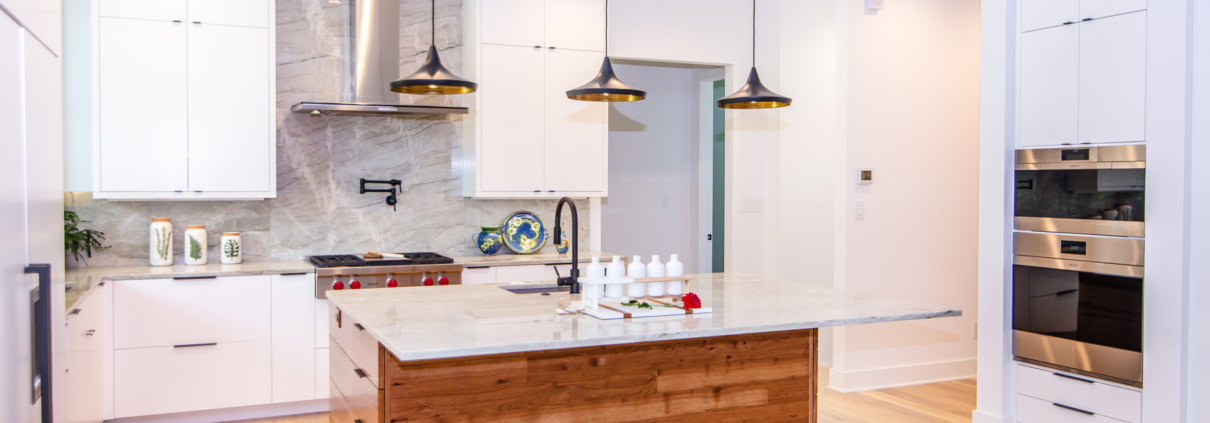 A kitchen with white cabinetry and a wood island