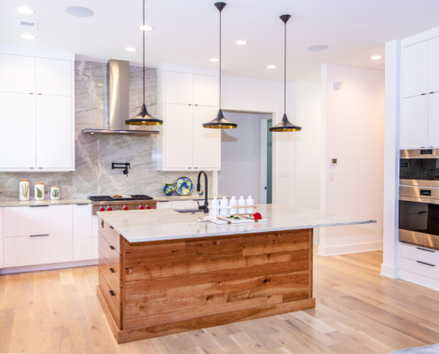 A kitchen with white cabinetry and a wood island