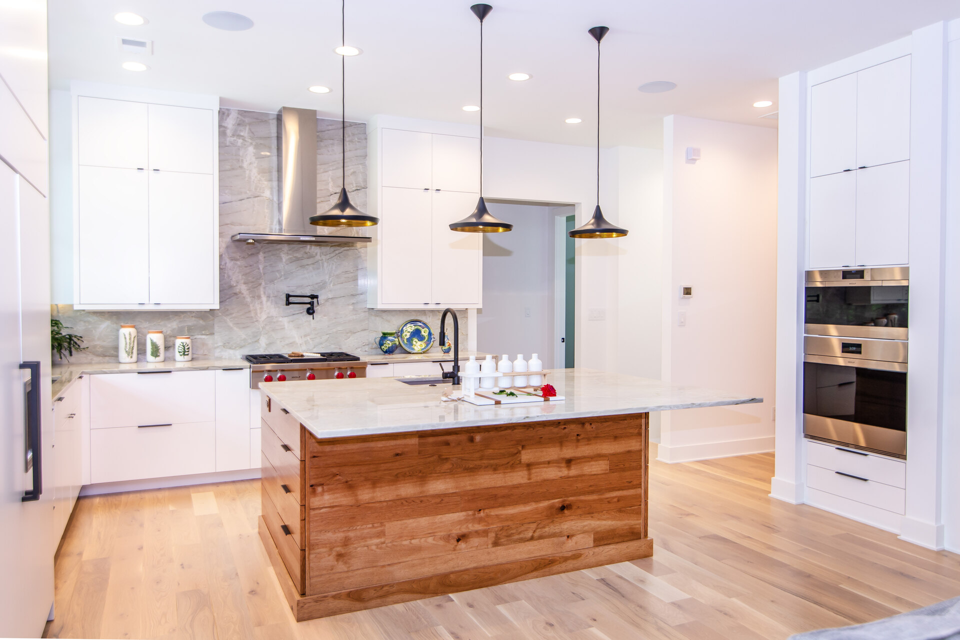 A kitchen with white cabinetry and a wood island
