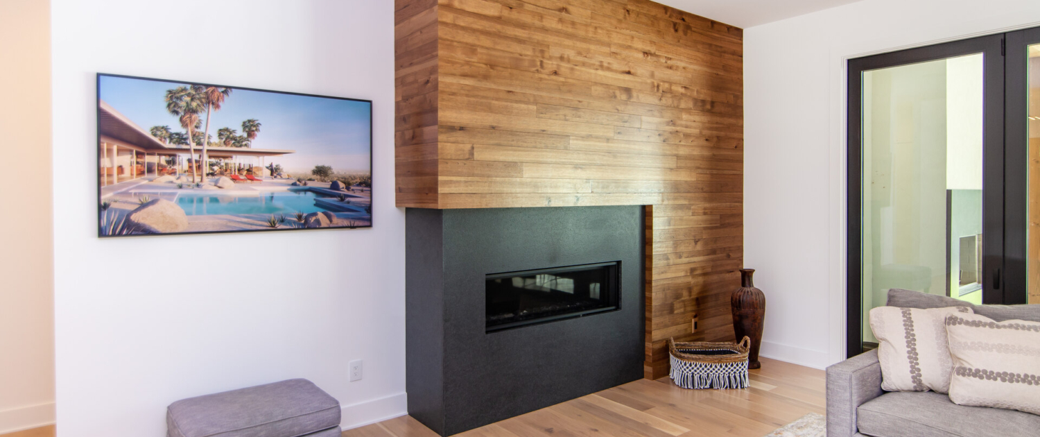 A living room with a black fireplace and a wood wall built around it