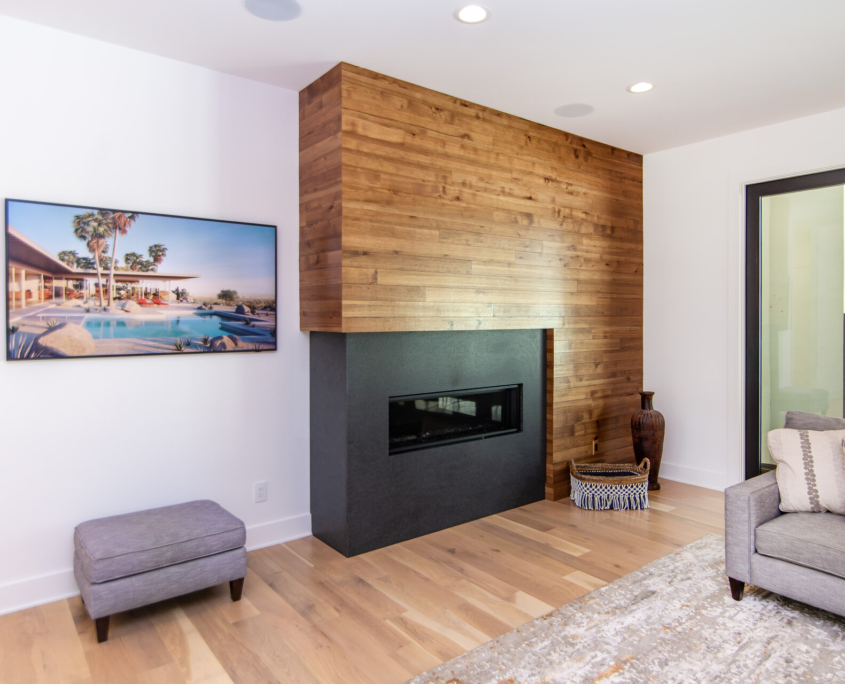 A living room with a black fireplace and a wood wall built around it