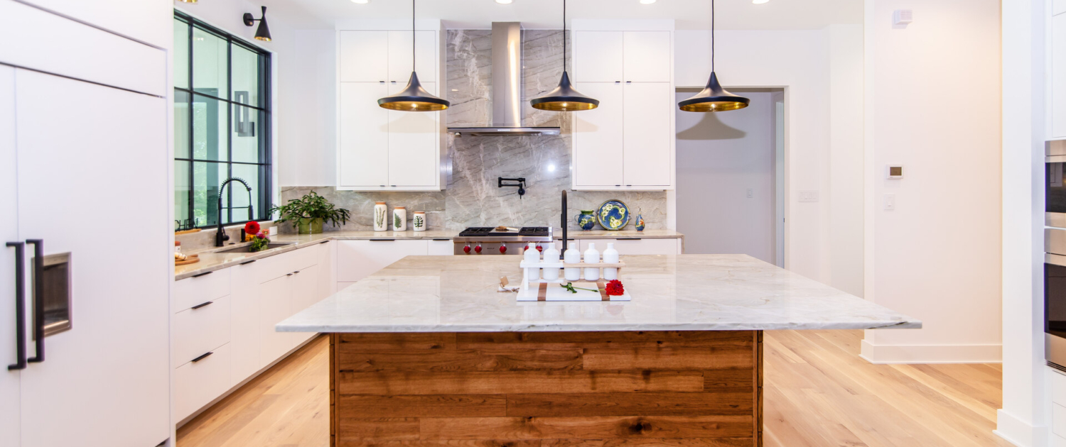 A kitchen with white cabinets and a wood island