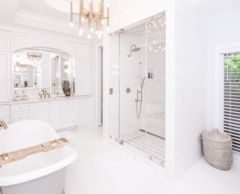 White bathroom with large light fixtures and a tub and shower