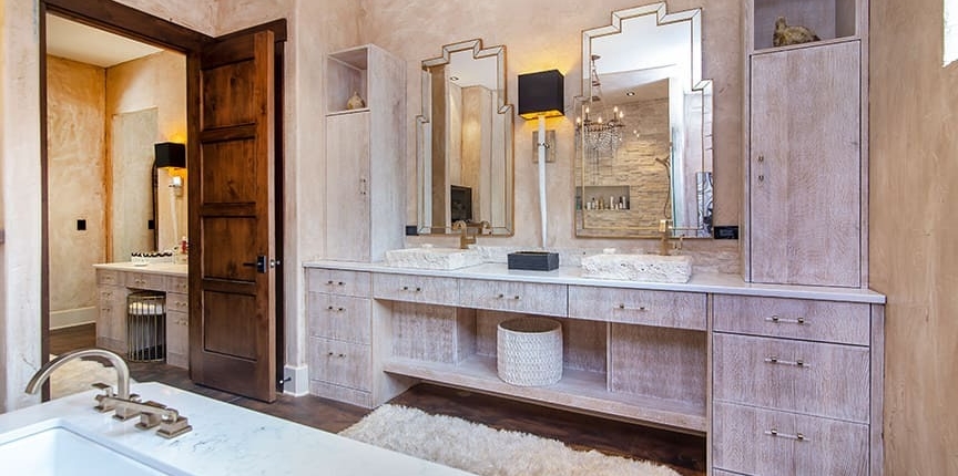A master bathroom with a double cabinet vanity and storage area