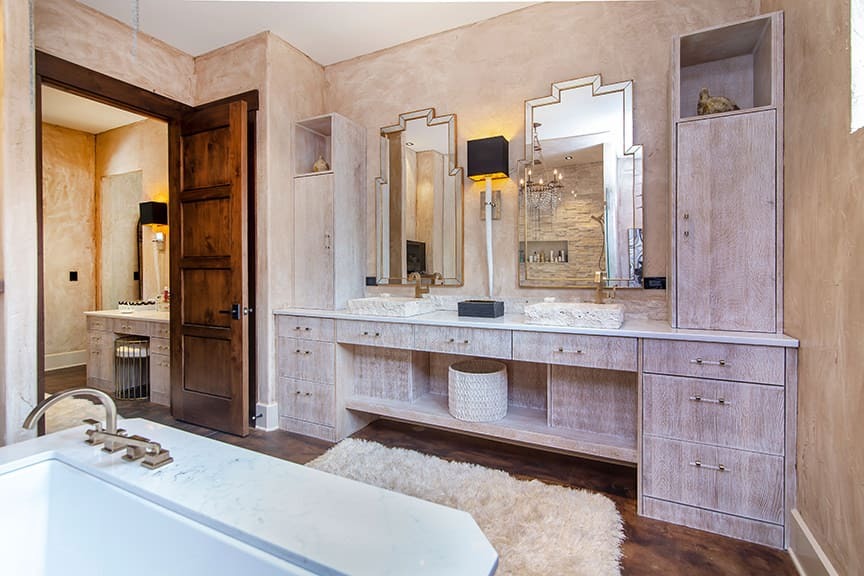 A master bathroom with a double cabinet vanity and storage area