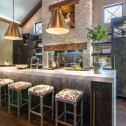 A kitchen with custom cabinetry and with a waterfall countertop and bar stools
