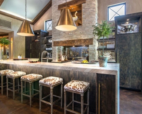 A kitchen with custom cabinetry and with a waterfall countertop and bar stools
