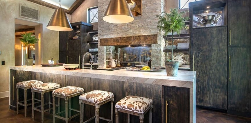 A kitchen with custom cabinetry and with a waterfall countertop and bar stools