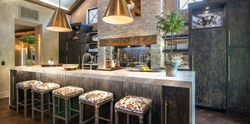 A kitchen with custom cabinetry and with a waterfall countertop and bar stools