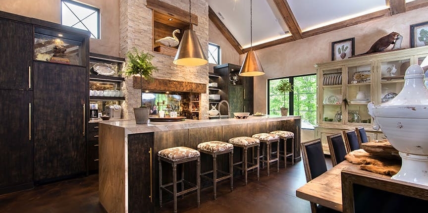 A kitchen with black cabinetry and a waterfall countertop with custom lighting