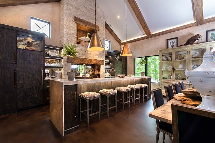 A kitchen with black cabinetry and a waterfall countertop with custom lighting