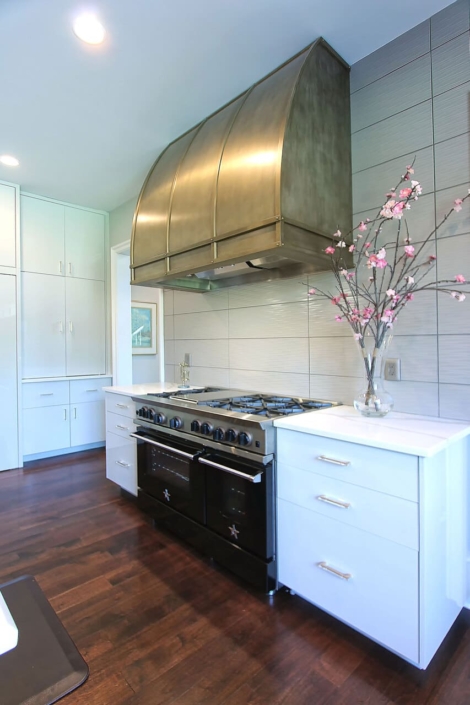white kitchen with a gold hood and flowers