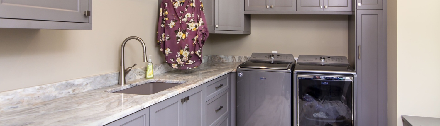 Grey laundry room cabinets with marble countertops