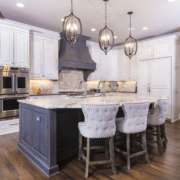 White kitchen cabinets with a brown island and large light fixtures
