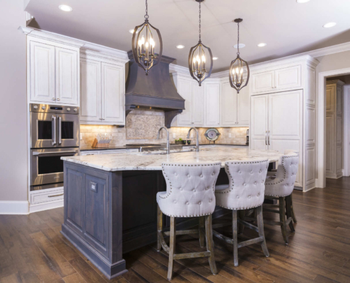 White kitchen cabinets with a brown island and large light fixtures